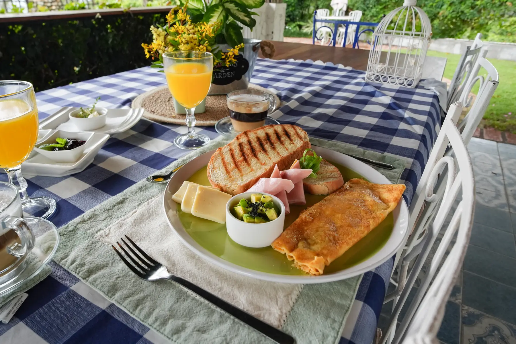 Desayuno con arepa, omelette, fruta y jugo servido junto al jardín